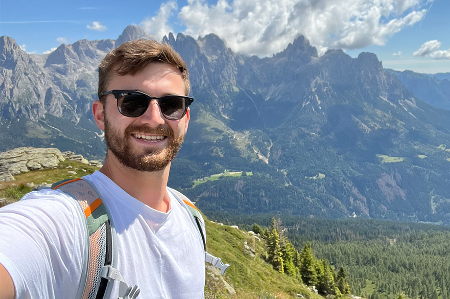 Joe smiling at the camera whilst on a hike through the mountains