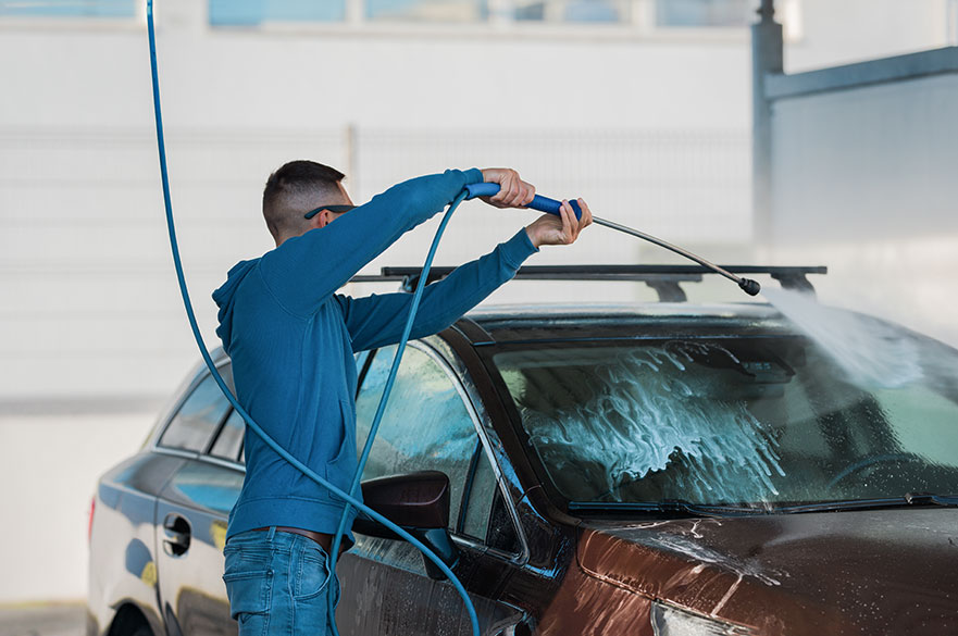 man washing a car with a jet spray