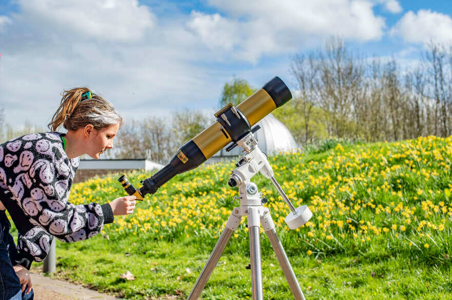 A student using a telescope outdoors