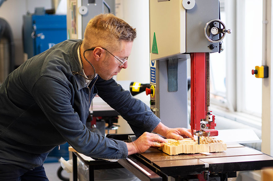 Technician cutting wood using electric saw