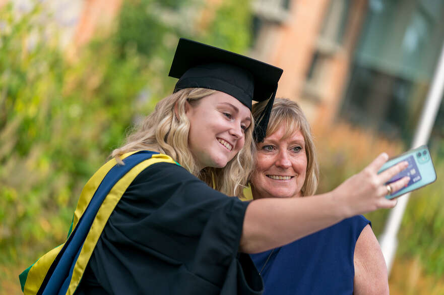 Student and parent taking a selfie after graduation.