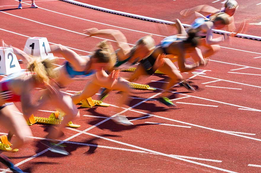 Motion shot of women on the athletics track starting line