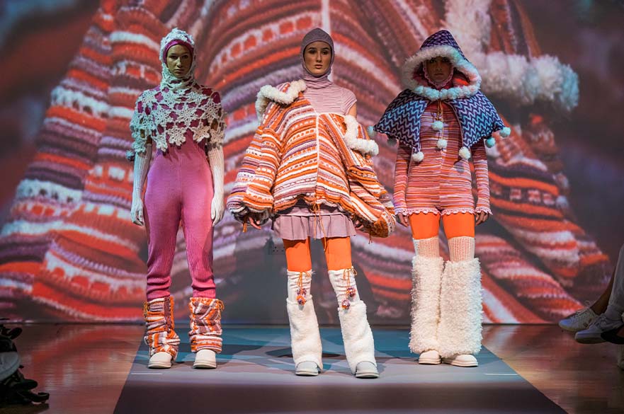 3 models posing at graduate fashion week, wearing knitted textile outfits
