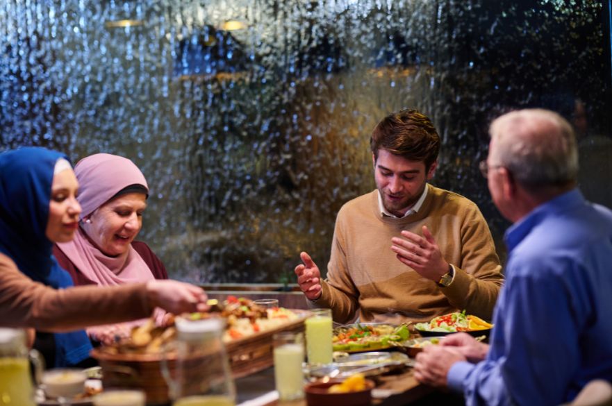 Family sharing food in a restaurant looking happy while there is heavy rain outside