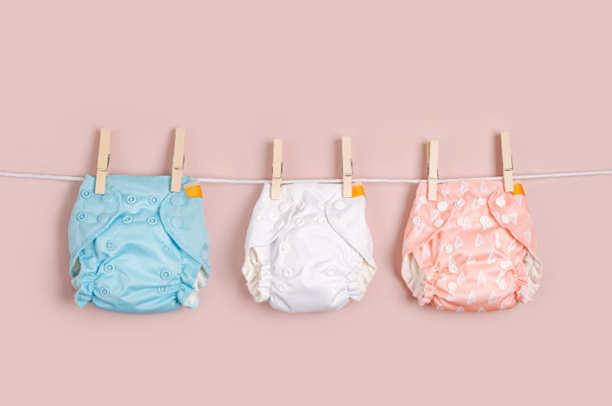 Three cloth nappies on a clothes line with a pink background