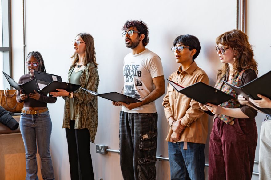 A group of students singing and holding music. 
