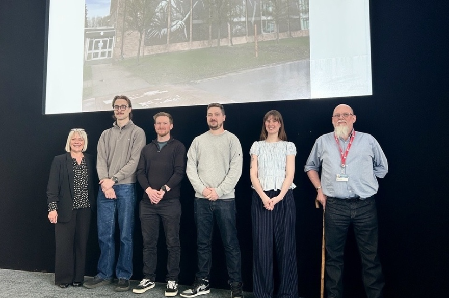 A group of people stood on a stage having their picture taken.