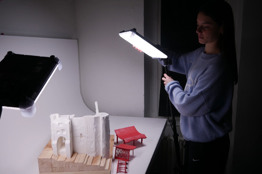 An architecture student photographing a model of their work.