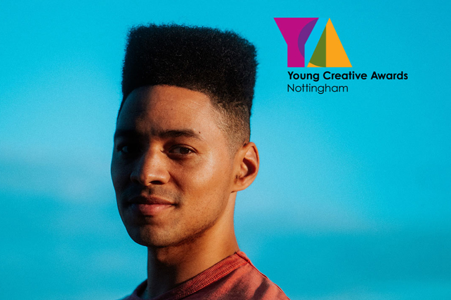 A young man looking into the camera against a blue background.