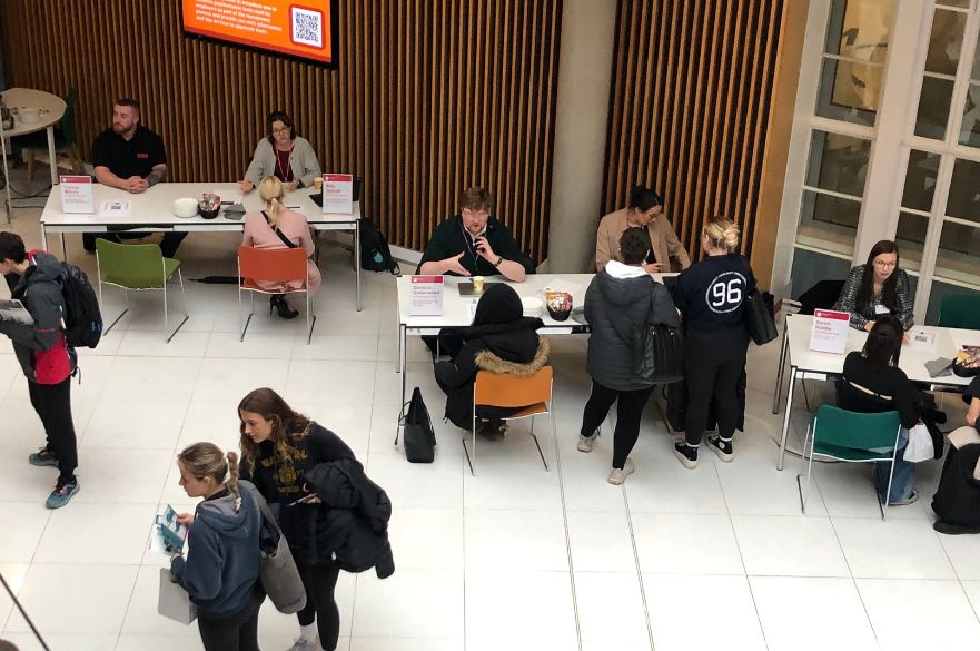 View looking down on students and Alumni Fellows around tables