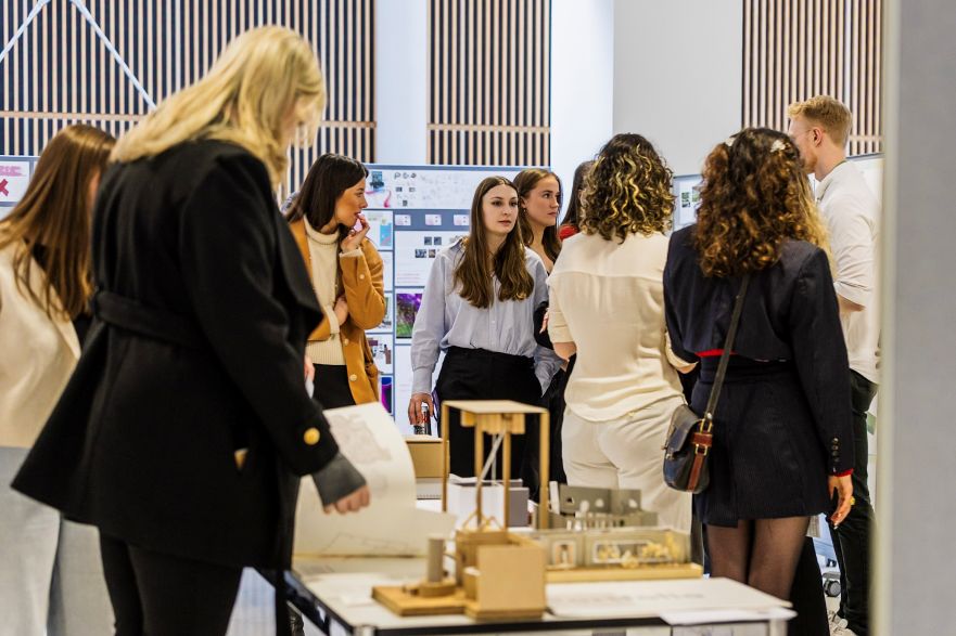 A woman is looking at a model of an architectural design with other people standing in the background