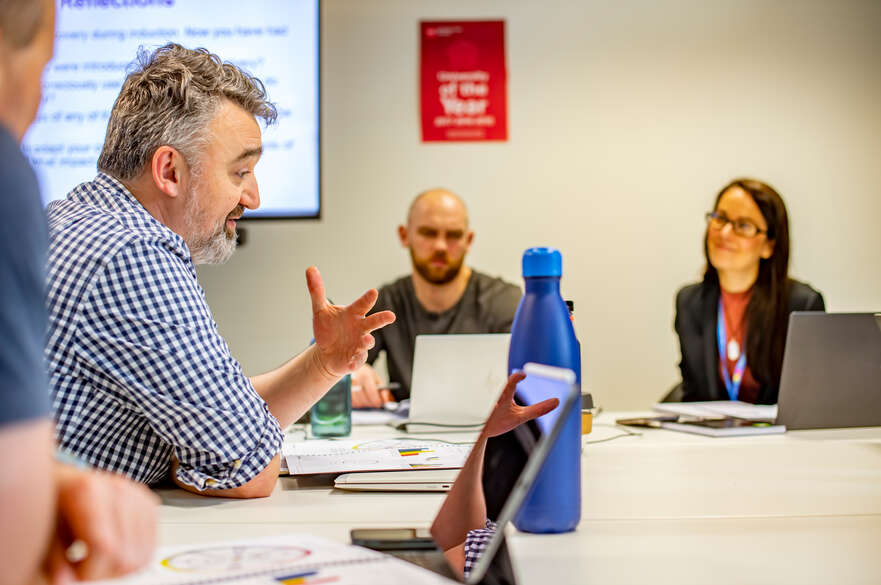 A meeting taking place inside a classroom between four people