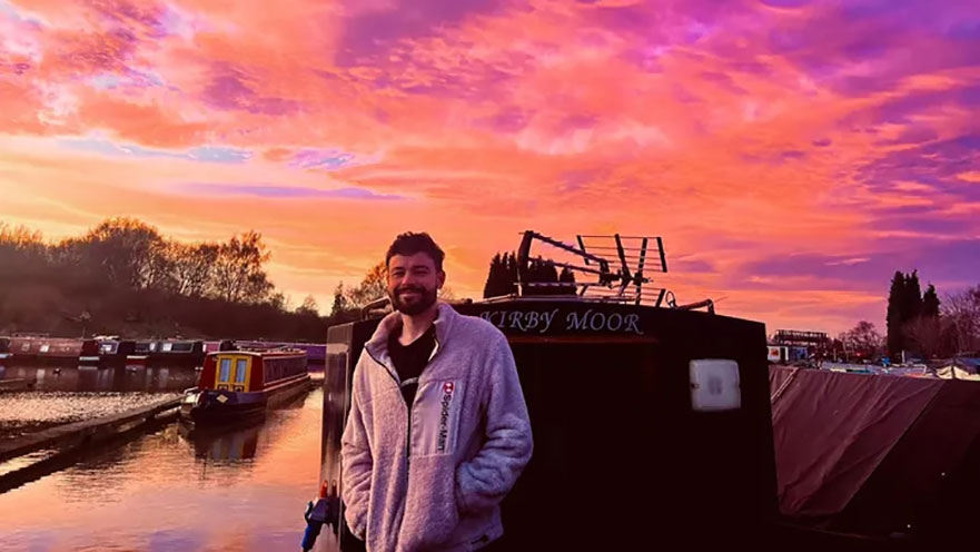 Rian Rogers, standing on a boat at sunset.