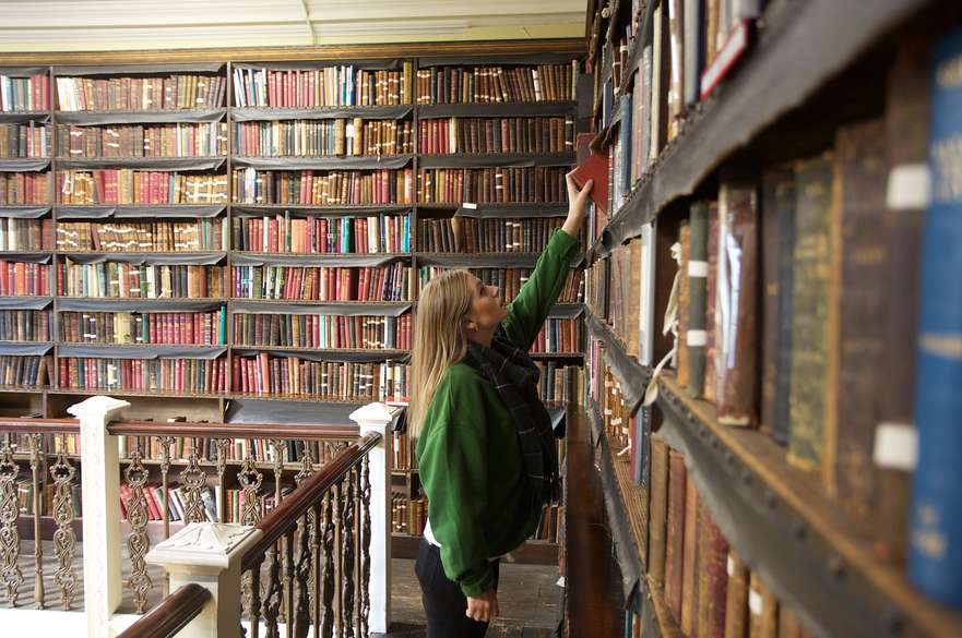 student reaching for book