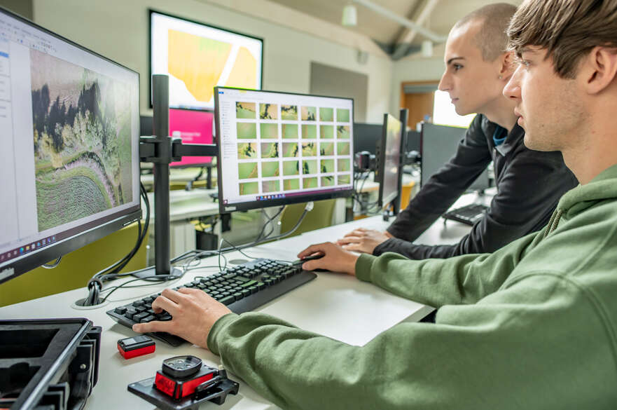 Two students analysing GIS data on computer monitor