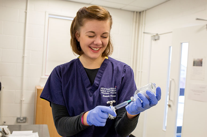 Student smiling and drawing medicine from a bottle into a syringe