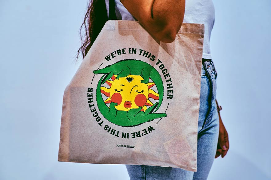 A canvas tote bag featuring a sun and alligator design with the phrase 'We're in this together.' Promoting NTU’s 'Solving Wicked Problems' summer course for 15-17-year-olds, focused on collaboration, critical thinking, and global challenges.
