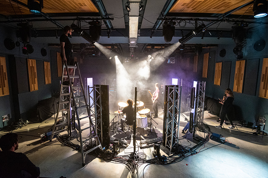 A band plays while students use lighting equipment that illuminates the band