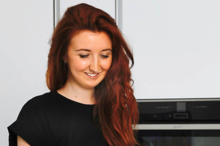 a young, white woman with long brown hair is looking down and smiling