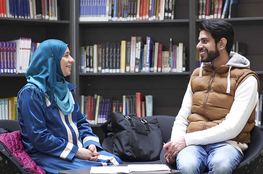 man and woman sat in library at desk