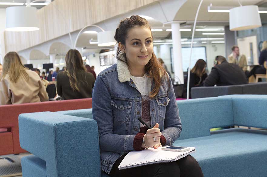 Girl sat on sofa with notebook