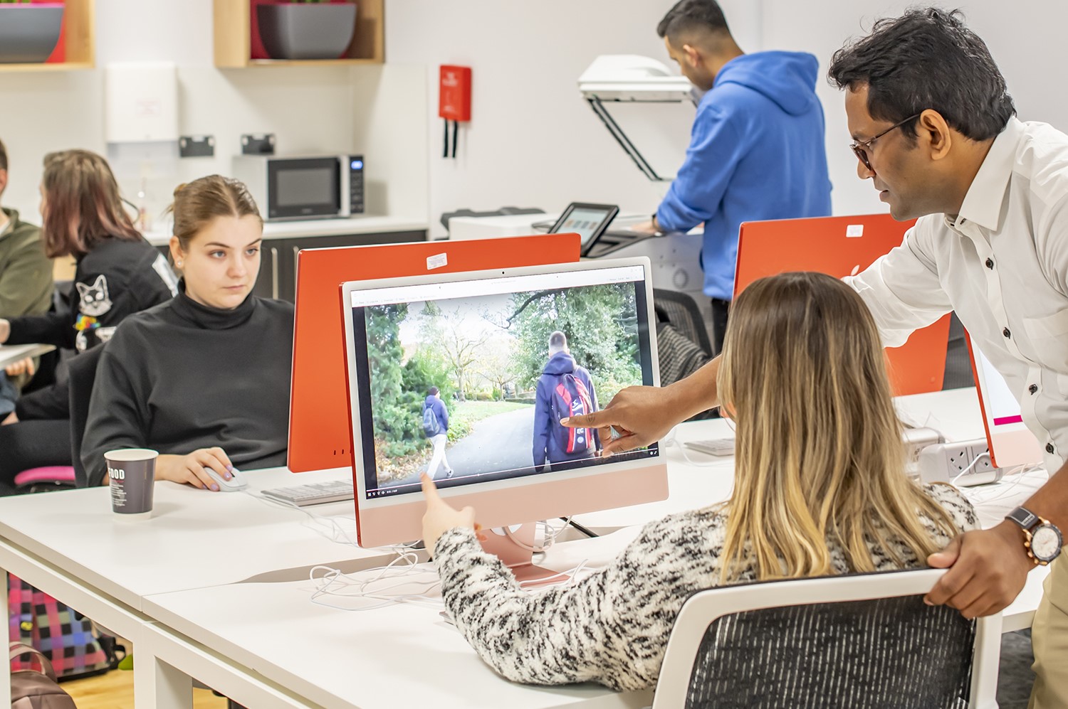 A media student is advised on their work by a colleague