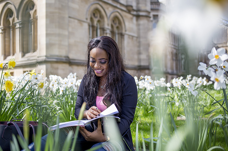 Student reading book on Arkwright lawn in the sun