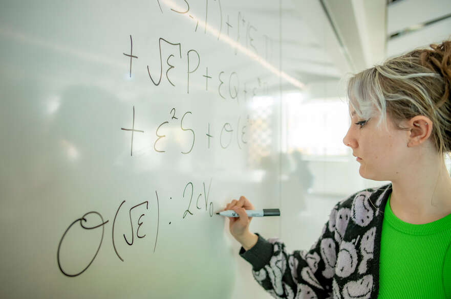 Student writing mathematic equations on the board