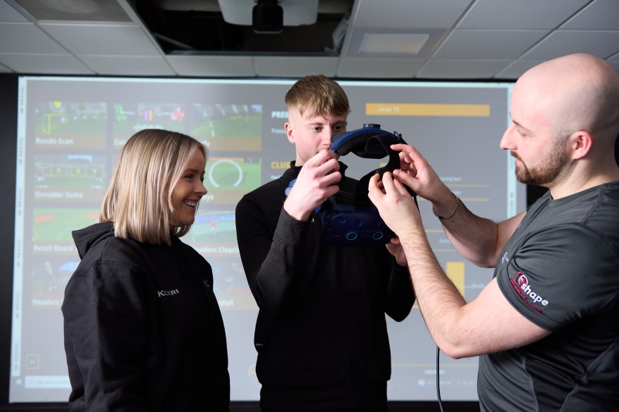 Two students and a member of staff using a VR headset