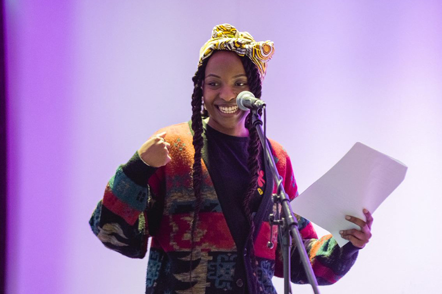 A women performing onstage holding a sheet of paper.
