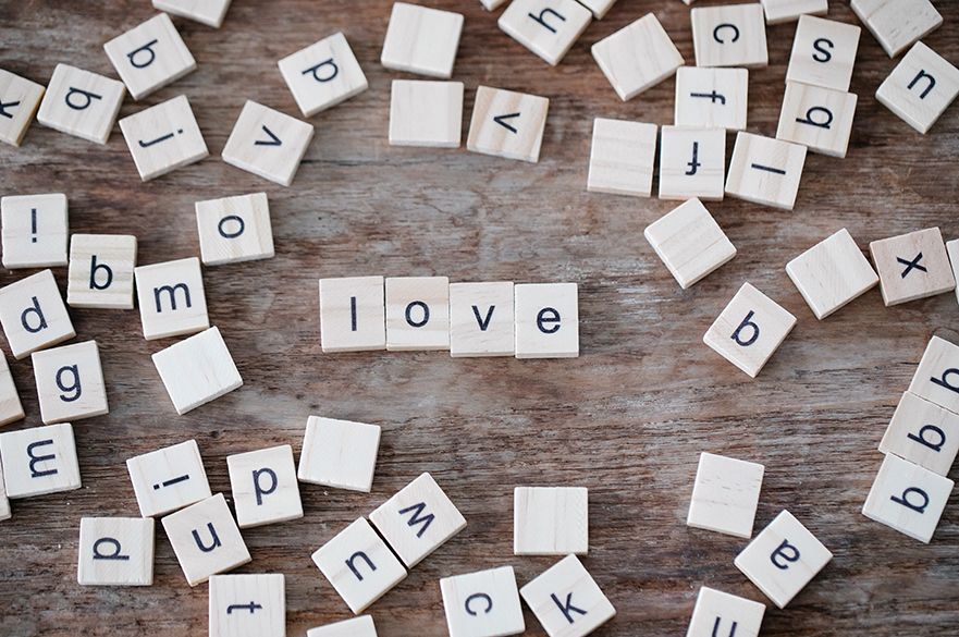 Love spelt out in scrabble tiles with random tiles placed around the outside.