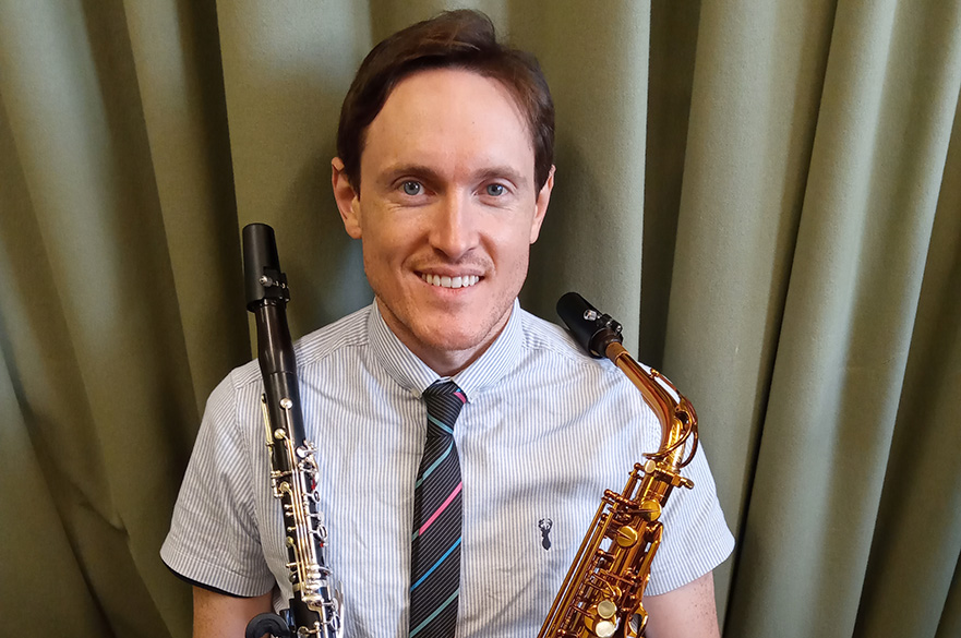 Male holding saxophone and clarinet.