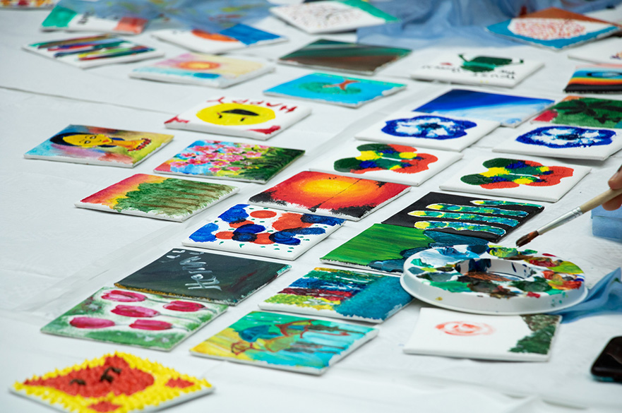 Lots of different painted tiles on a table.