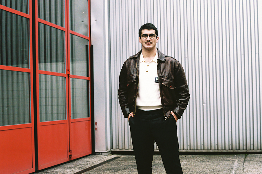 A man wearing glasses standing in front of a red window