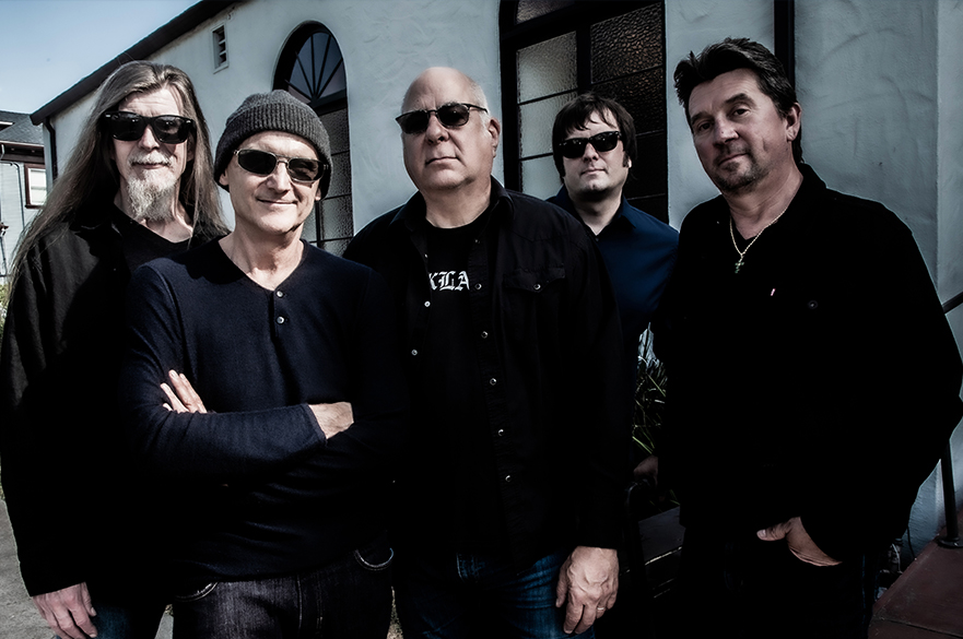 Photograph of 4 men wearing black clothes in a court yard.