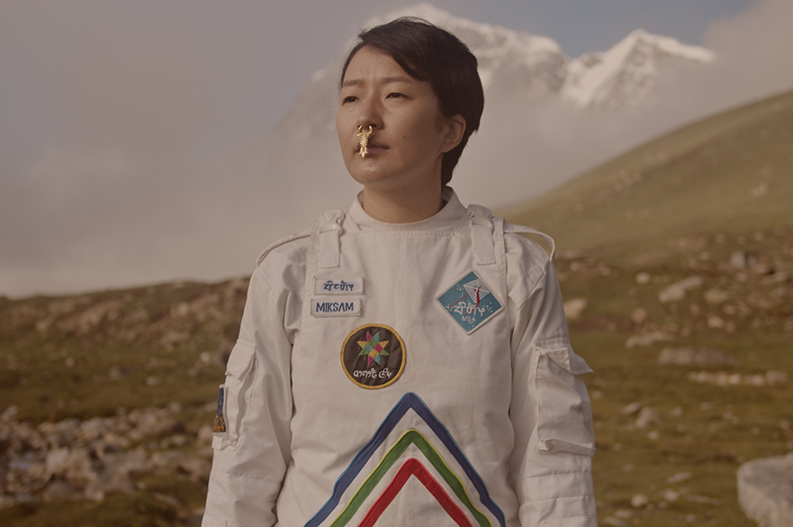 A person stood in a white astronaut-like suit with a gold nose piercing.