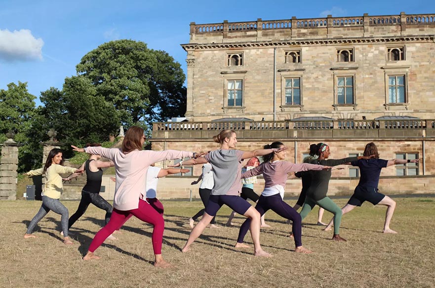 Students wearing comfortable clothes posed in movement on the lawn in front of a grand building.
