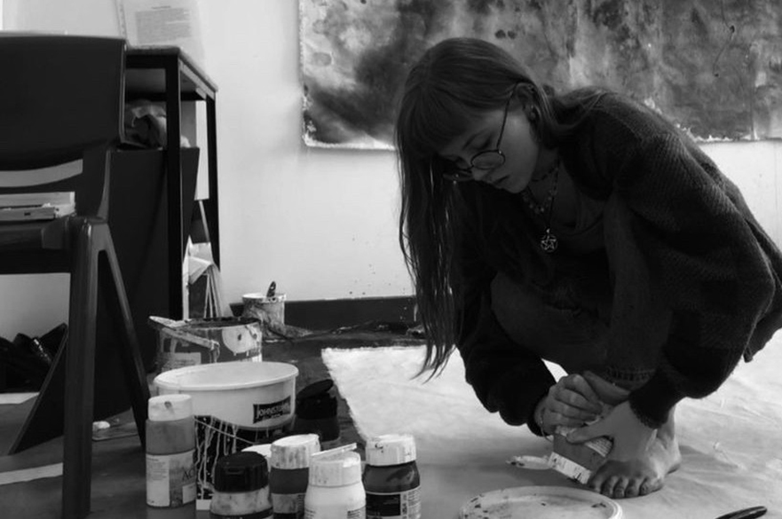 Artist Charlie Love crouched on the floor of her studio, squeezing paint into a palette.