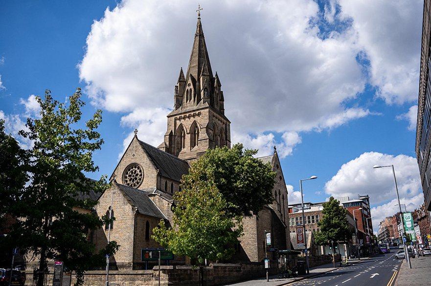 A stone cathedral next to a road that goes uphill.