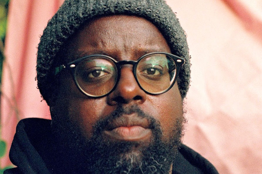 A close-up of a man wearing glasses and a beanie.