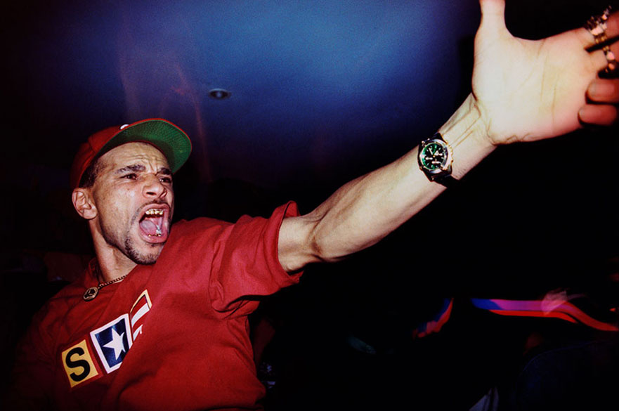 A man in a red cap and t-shirt against a dark background.