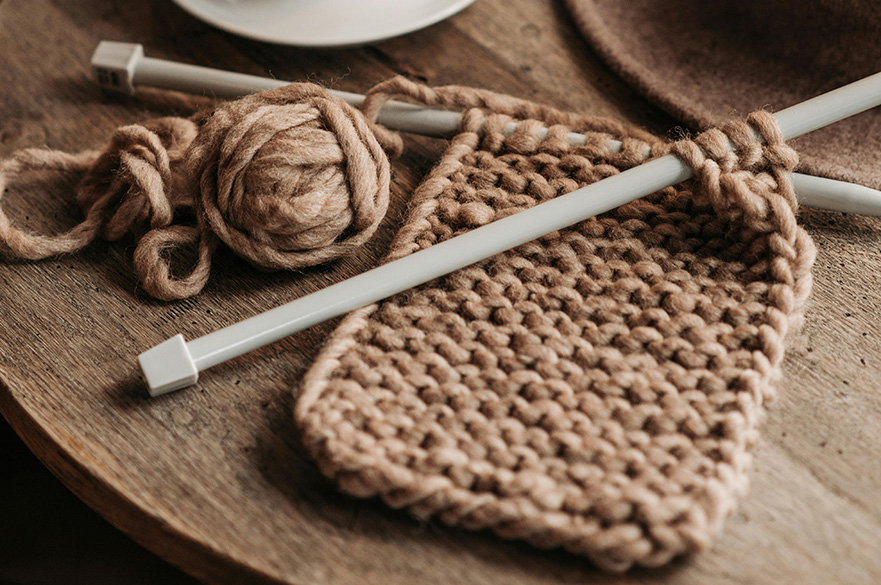 Yarn on a wooden table with two knitting needles