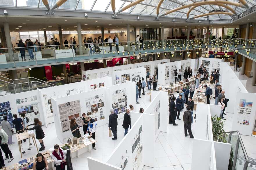 A view of people browsing student work in an exhibition.
