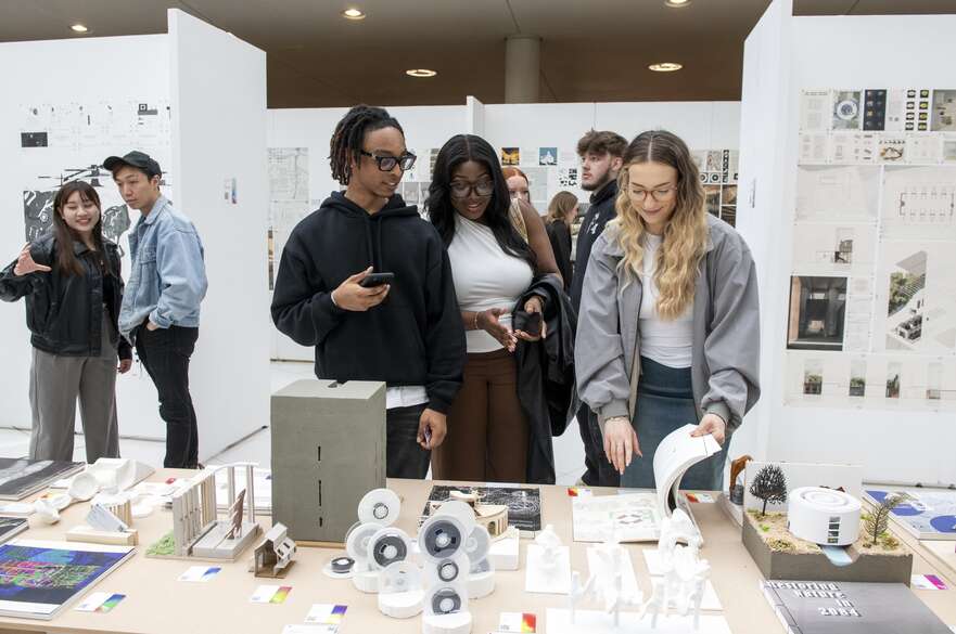 A group of people looking at a display of students' work on a table.