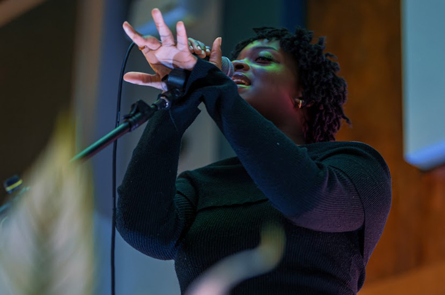 A black woman singing into a microphone.