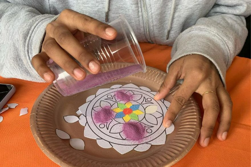 student making rangoli sand art