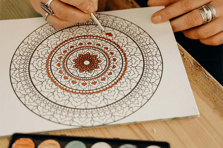 person colouring in a mandala pattern on picture