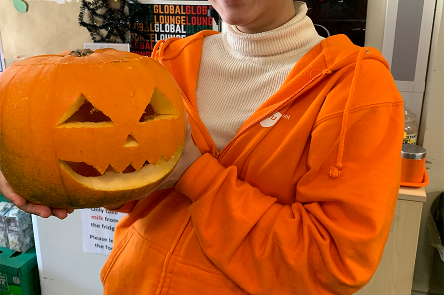 global lounge ambassador holding a carved pumpkin for Halloween