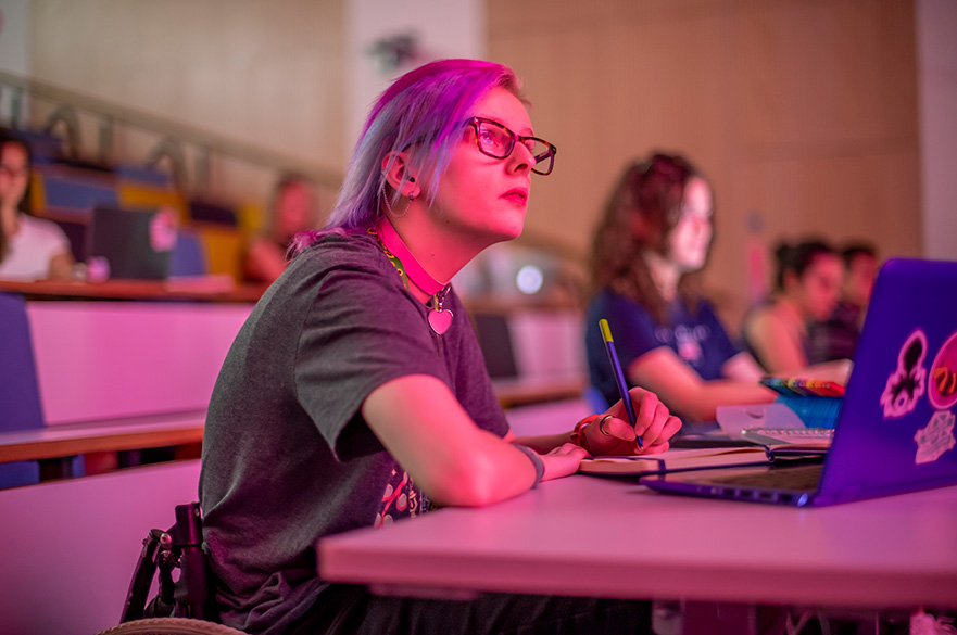 An NTU student taking notes in a lecture theatre