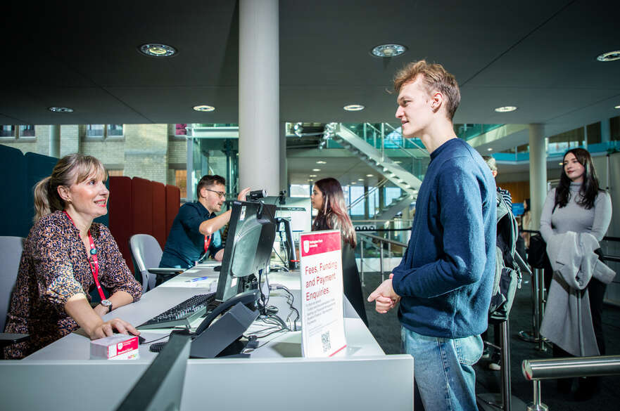 A student being served at the Student Services desk in the Newton building.